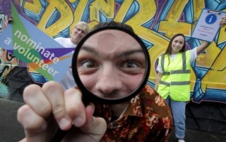 Photograph of James Kavanagh with magnifying glass and and two volunteers, Lorena and Carol