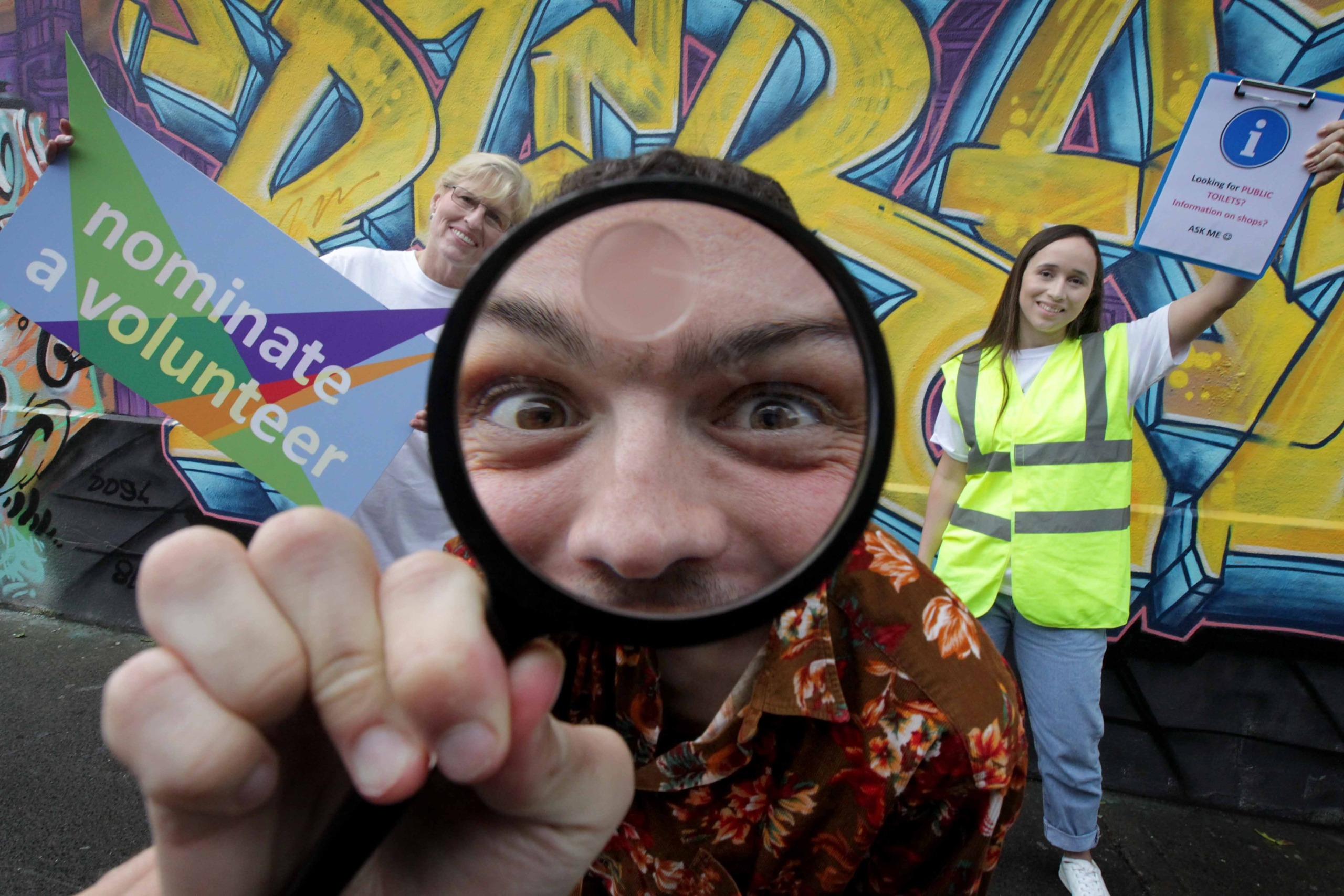 Photograph of James Kavanagh with magnifying glass and and two volunteers, Lorena and Carol